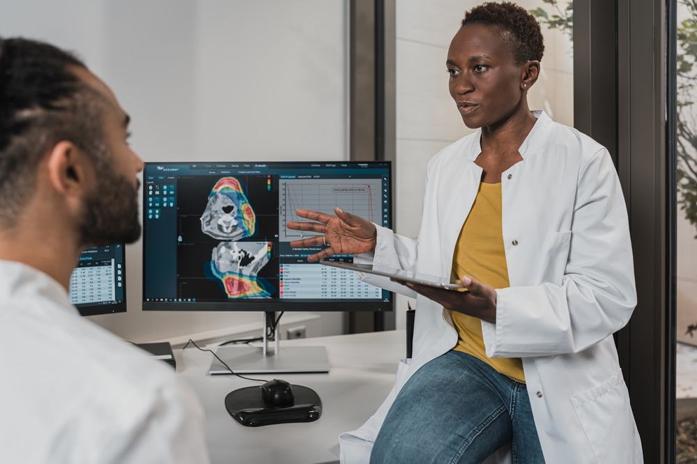 Two clinicians reviewing scans on a monitor