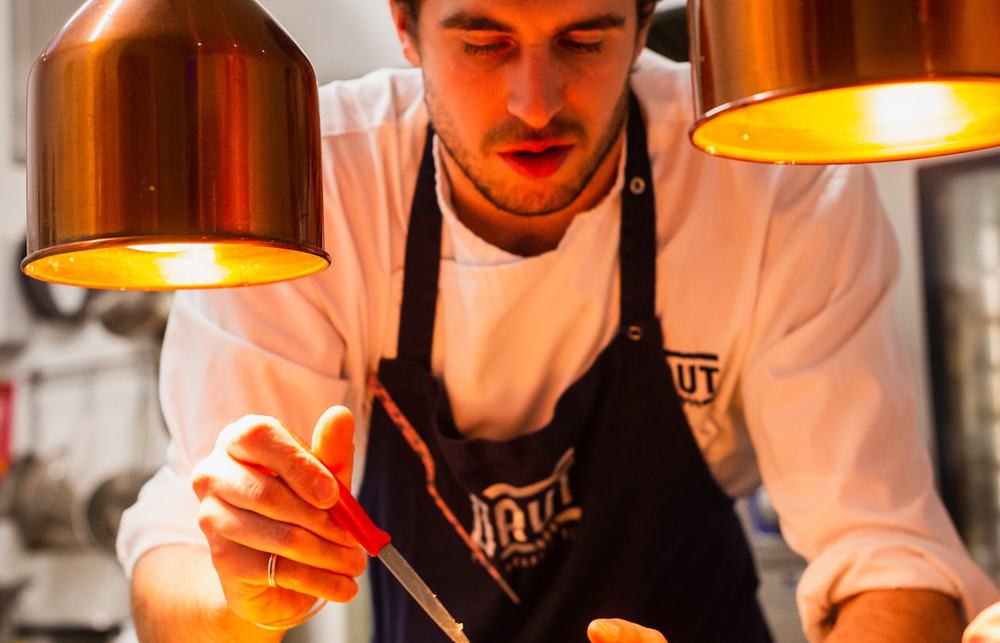 Chef plating a dish on a restaurant pass